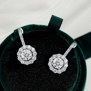 Close-up of 925 sterling silver halo moissanite stud earrings on green velvet box