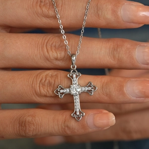 925 sterling silver cross pendant necklace with moissanite stones held by a hand