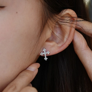 Close-up of s925 silver cross earrings with moissanite pave diamonds worn by a model