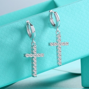Macro shot of silver cross earrings with shimmering moissanite set on a teal gift box