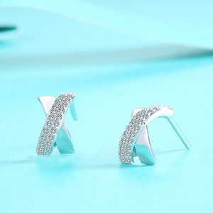 Detail of S925 sterling silver cross earrings with pavé stones on a blue background