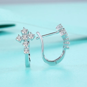 Gros plan de boucles d'oreilles créoles croix en argent avec pierres de moissanite brillantes