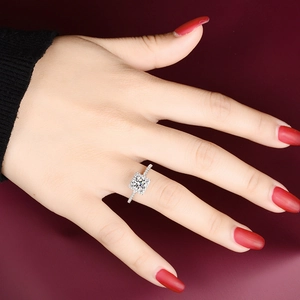 Close-up of a square-cut moissanite ring with a diamond-encrusted halo and band on a hand