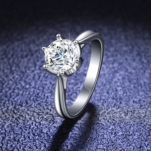 Macro shot of silver six-prong moissanite ring showing brilliant cut stone fire on blue background