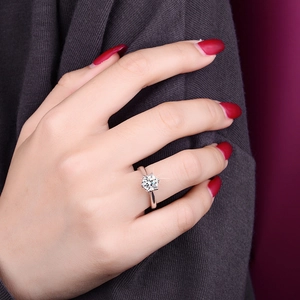 Detailed view of a classic six-prong solitaire moissanite ring on a female finger