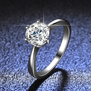 Detail of classic six-prong moissanite ring with round cut stone on a dark background