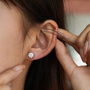 Classic round moissanite stud earrings in a four-prong s925 silver setting on model