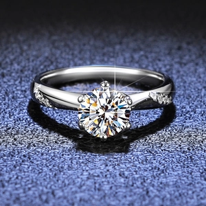 Macro shot of a classic six-prong moissanite ring with side stones on a blue background
