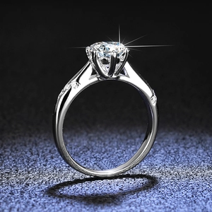 Macro detail of six-prong moissanite ring with side accent stones and silver finish
