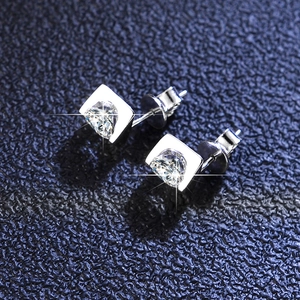 Macro view of heart-shaped moissanite earrings with silver studs on a blue textured background