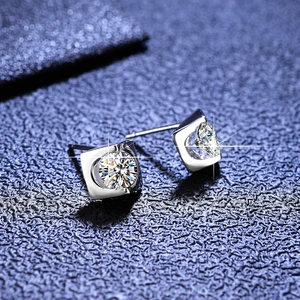 Macro shot of Moissanite stud earrings featuring square sterling silver settings on blue fabric