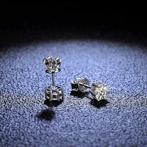 Macro shot of silver S925 six-prong moissanite stud earrings on navy leather display