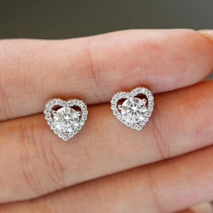 Sparkling S925 sterling silver heart-shaped moissanite stud earrings shown on finger
