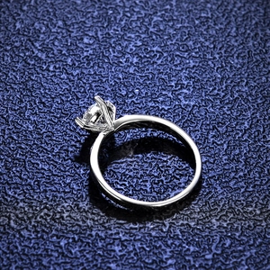 Classic six-prong moissanite ring with round brilliant cut stone on a navy background