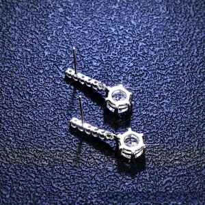 Close-up of sparkling six-prong moissanite earrings with elegant silver linear tassels