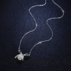 S925 silver bow pendant necklace with 1 carat moissanite on blue leather background
