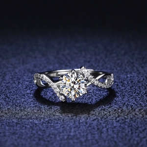 Moissanite ring featuring a brilliant round cut stone with a twisted pavé silver band