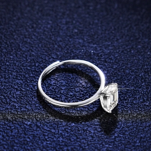 Emerald cut moissanite sterling silver ring with adjustable band on blue fabric