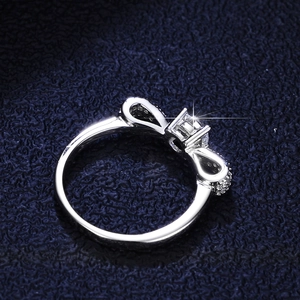 Elegant 925 sterling silver bow ring with sparkling moissanite stones on blue texture