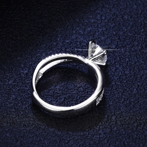 Elegant six-prong moissanite ring with twisted pavé band on dark leather background