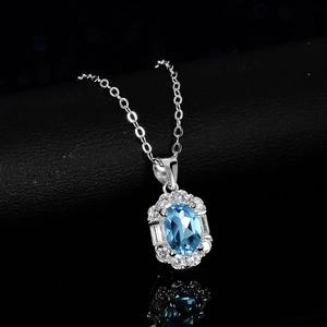 Collier en argent avec pendentif topaze bleue ovale et halo de diamants sur fond noir