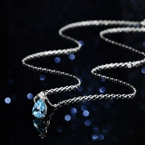 Elegant silver necklace with pear-cut blue topaz pendant and round moissanite accent
