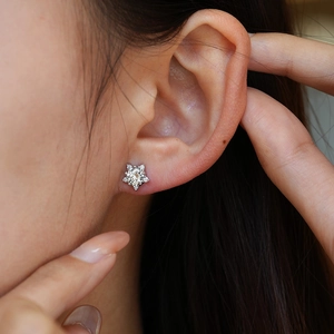 Star-shaped S925 sterling silver moissanite stud earrings worn by a model