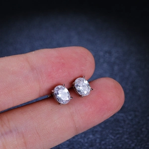 Close-up of s925 silver oval-cut moissanite stud earrings held for size reference