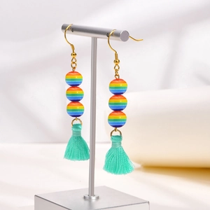 Dettaglio di perline arcobaleno colorate e nappe verde menta su orecchini a gancio