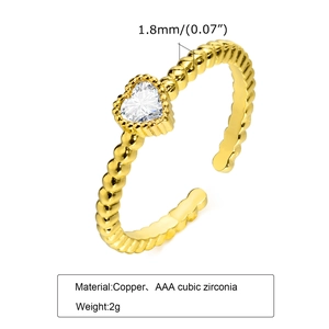 Dettaglio dell'anello a cuore dorato con zircone nero e fascia con trama a microsfere