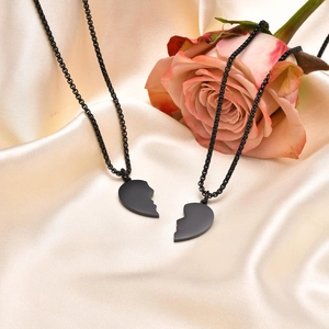Dettaglio delle collane per coppia a cuore nero su seta beige con una rosa rosa