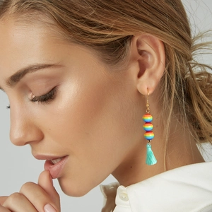 Dettaglio degli orecchini boho con perline arcobaleno e nappe blu indossati dal modello