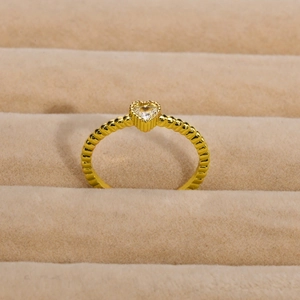 Dettaglio dell'anello con zircone a cuore e texture a perline su velluto beige