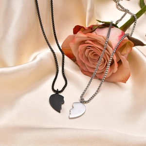 Dettaglio delle collane puzzle a cuore nero e argento su seta con una rosa