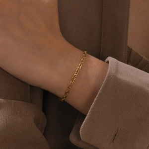 Bracelet chaîne à maillons marins en or 18 carats porté avec un blazer marron