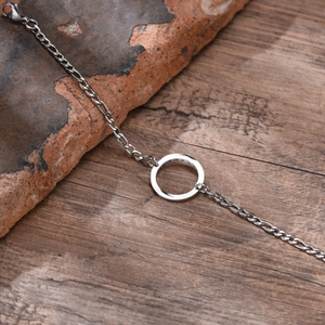 Detail of silver stainless steel chain bracelet with hollow circle on stone surface