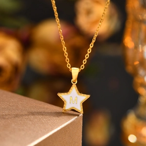 Detailed view of a gold star pendant with letter M inlay and bead edge on a chain