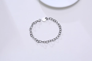 Détail du bracelet chaîne en acier argenté avec breloque ronde et fermoir homard