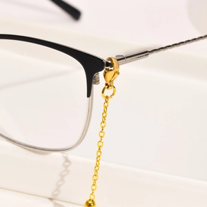 Macro shot of gold stainless steel lobster clasp and chain attached to eyewear frame