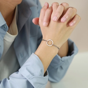 Minimalist stainless steel circular ring bracelet with NK chain shown on a model wrist