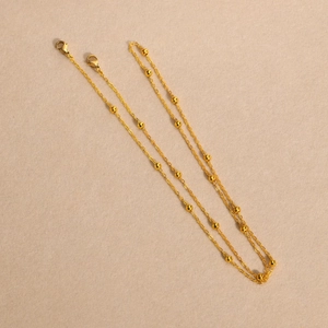 Detailed macro view of golden seed bead chain with lobster clasp and metal spacers