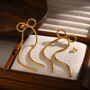 Boucles d'oreilles nœud dorées avec glands en chaîne serpent sur coffret à bijoux