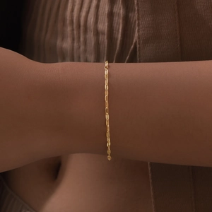 Detailed view of an 18K gold-plated stainless steel flat oval link bracelet on wrist