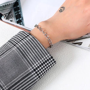 Bracelet minimaliste en acier inoxydable argenté porté au poignet d'une femme élégante