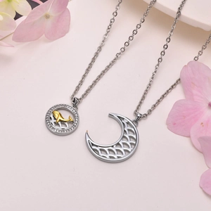 Detailed view of silver whale and crescent moon puzzle pendants with zircon on pink surface
