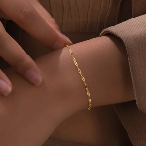 Detail of thin 18K gold plated stainless steel chain bracelet worn on a woman wrist