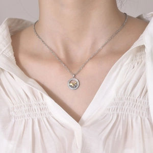 Detail of silver chain with zircon circle pendant and gold whale charm on model