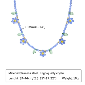 Gros plan d'un collier en perles de cristal bleu avec marguerites et feuilles vertes