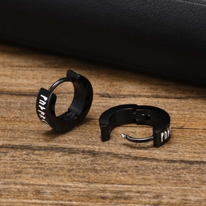 Detail of black stainless steel viking rune hoop earrings on a dark textured background