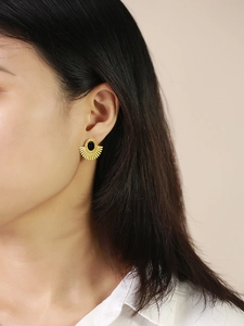 Detailed view of fan-shaped gold earrings with black stone inlay worn by a model